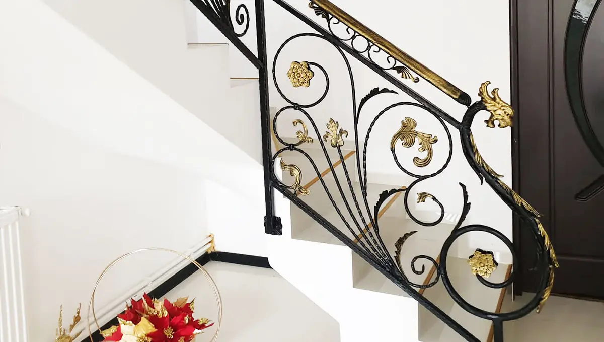 Balustradă cu elemente forjate și ornamente aurii la o scară exterioară