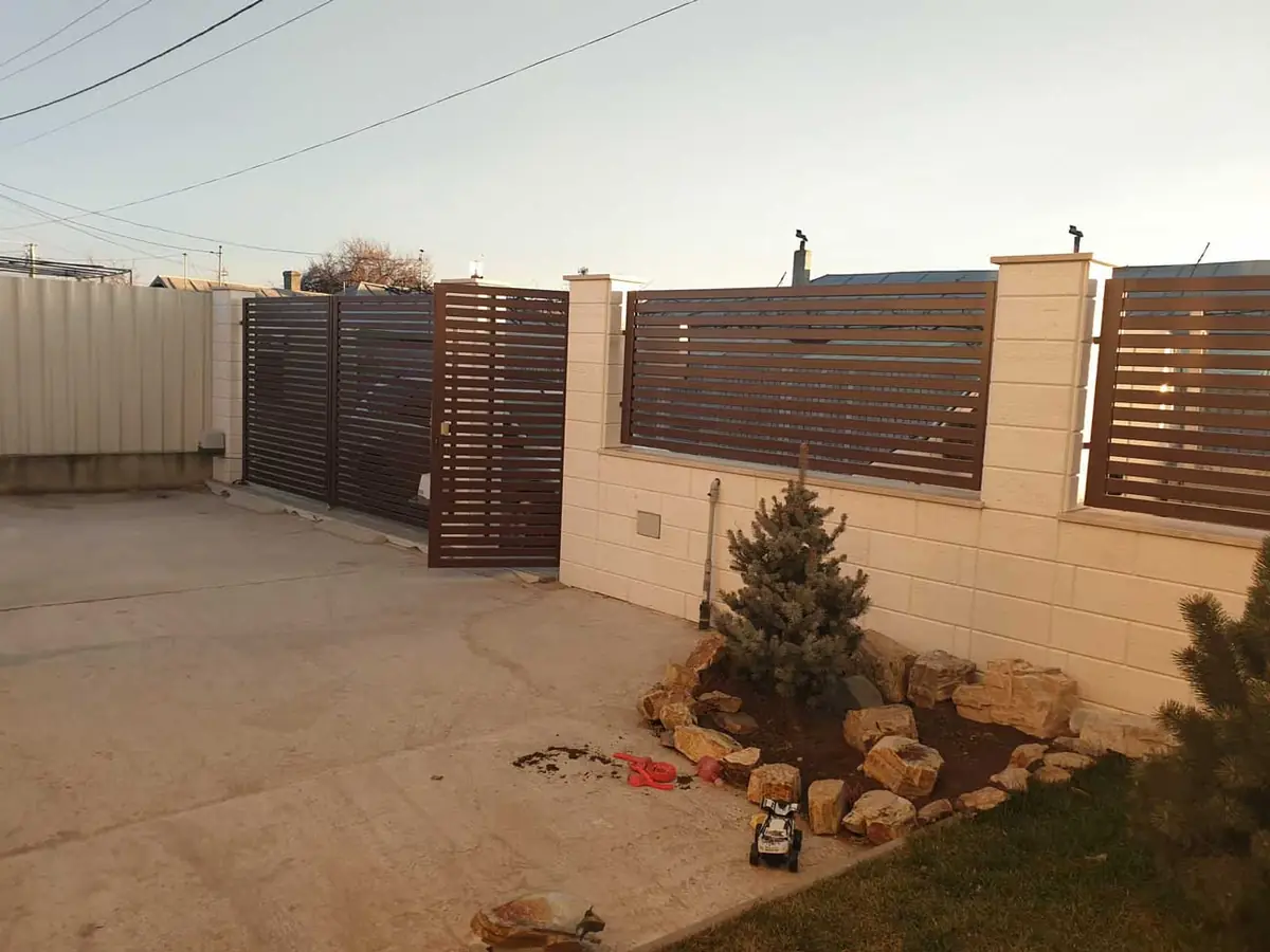 Gard de curte din panouri metalice cu lamele, între stâlpi de zidărie